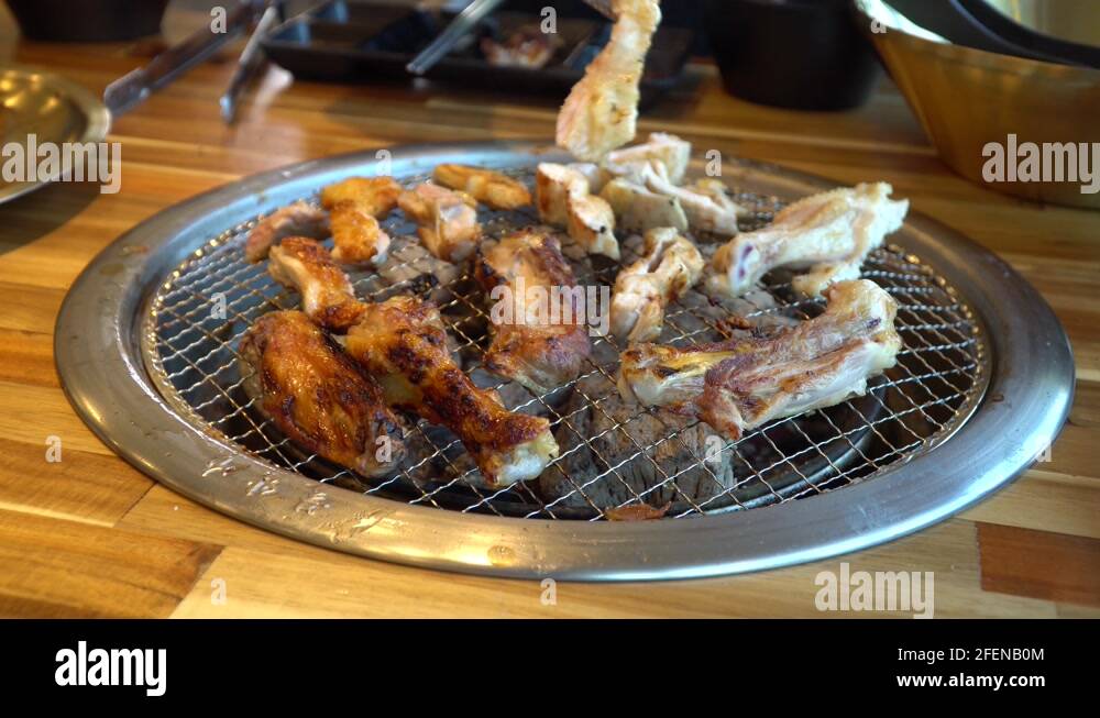 Korean Barbecue built in grill in table turning pieces of chicken in