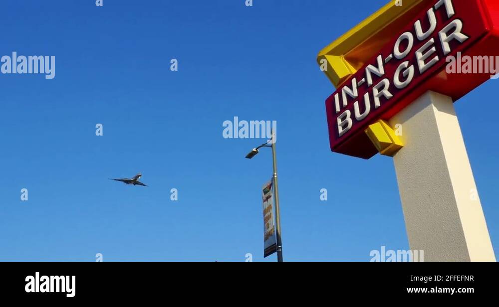 Jet plane approaching landing over InnNOut Burger sign near LAX