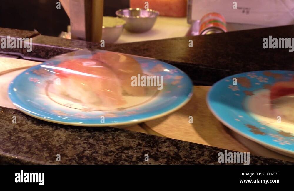 Sushi train plates with the sushi are placed on a rotating conveyor belt Stock Video Footage Alamy