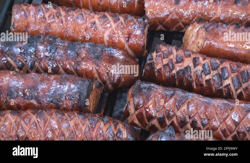 Panning left to right of cut polish sausages on the fire pit's grill