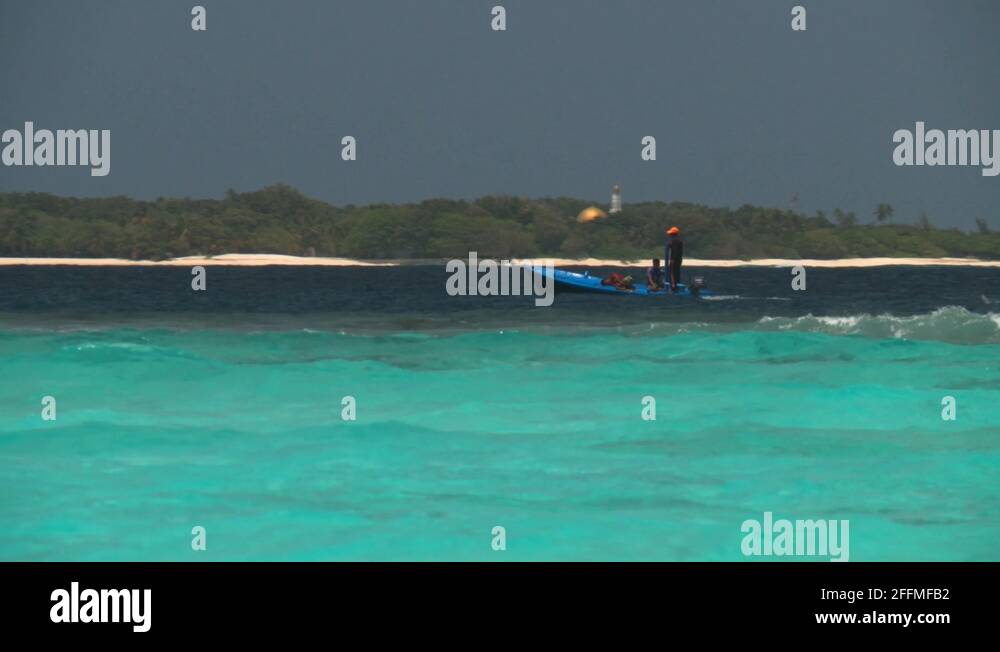 Fishermen on a boat pass a disappearing lowlying island in the