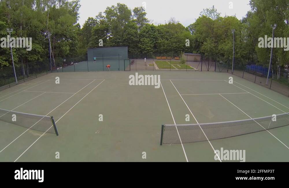 Two boys use wall for tennis training near courts in park Stock Video
