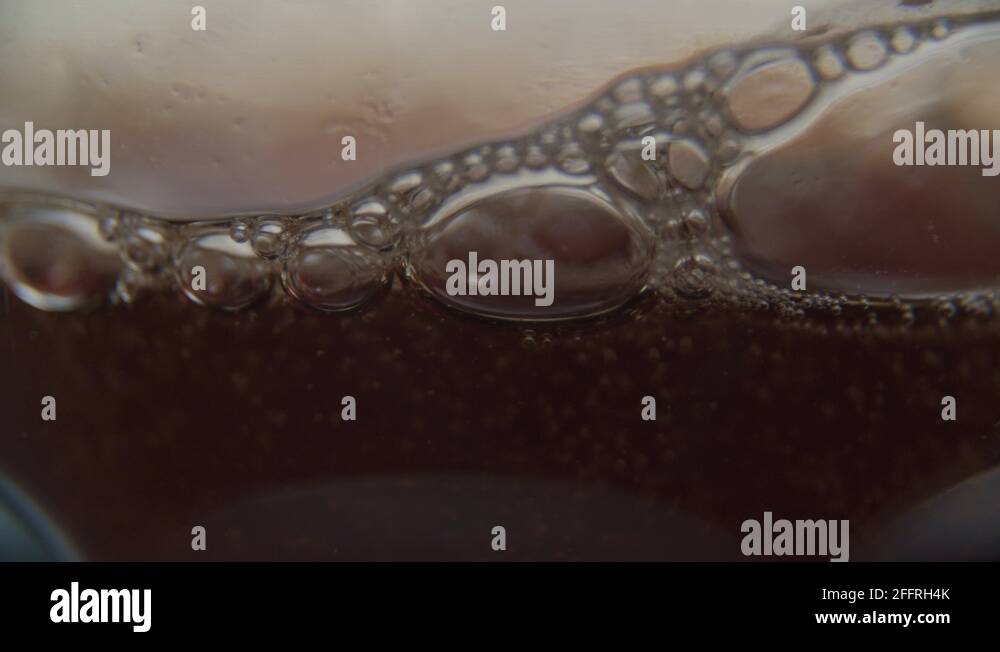 "Pouring fizzling coke/cola/soda into a glass on a table in a clean