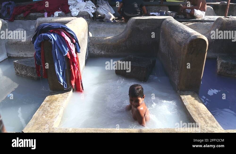 Boy playing in a washing pool filled with detergent in slum of Mumbai ...