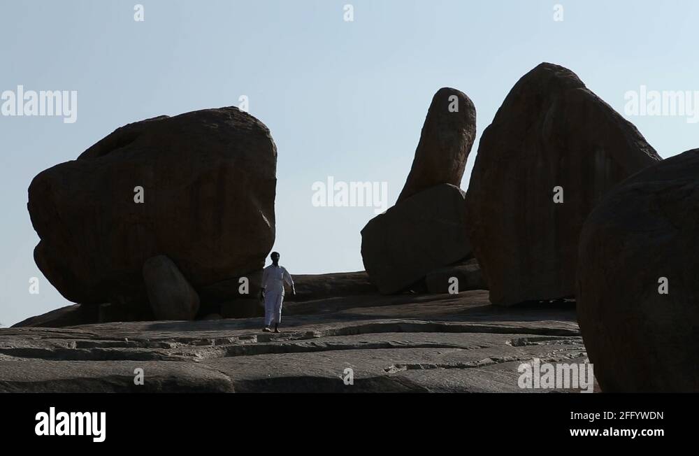 Indian man walking between large stones which have been used to make