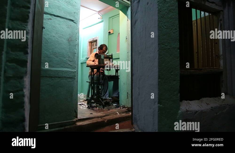 Man sewing on a sewing machine at the house entrance in Varanasi Stock