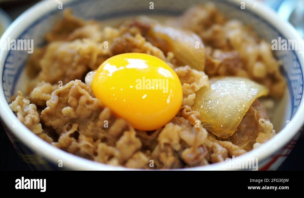 Delicious eating raw egg yolk on food. Japanese beef over rice Stock