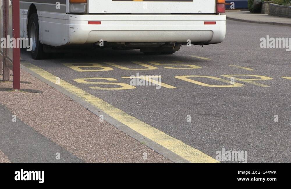 Low Angle Bus and Bus Stop Road Marking and Pedestrian in England Stock
