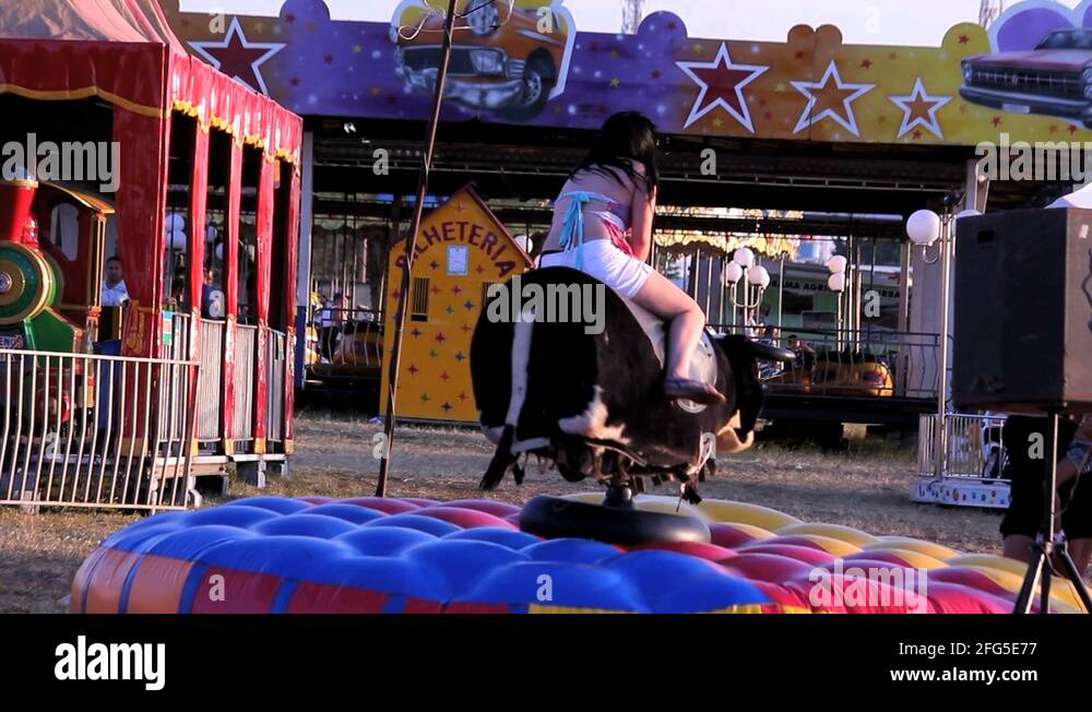 Girl riding mechanical bull at amusement park Stock Video Footage Alamy