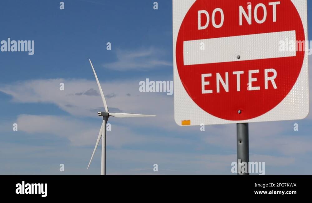 Wind Turbine Blades Rotate in Background of DO NOT ENTER Sign Stock