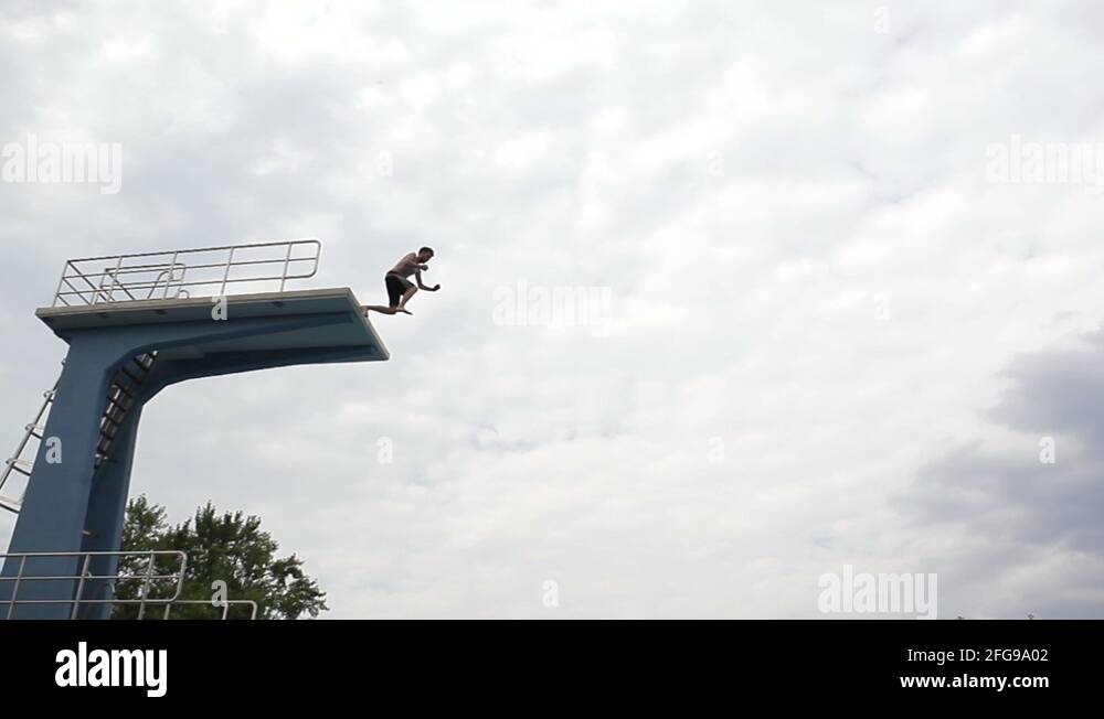 Scary jump from a high diving board into swimming pool Stock Video