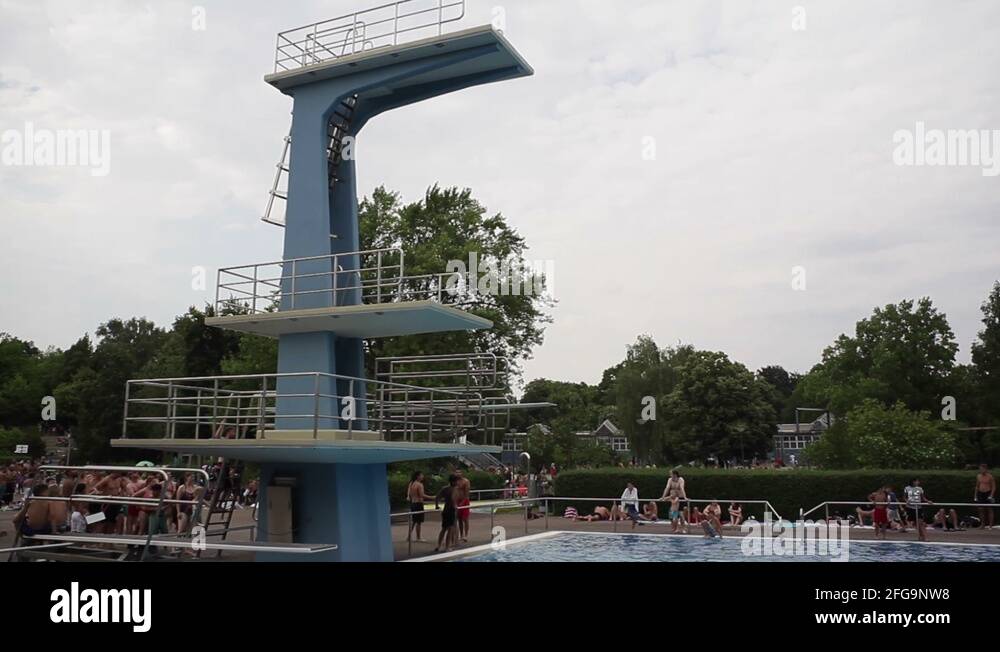 Man jumps backflip into a swimming pool from high diving board Stock
