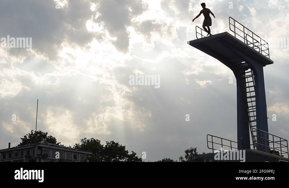 Man jumps from high diving board into public swimming pool Stock Video