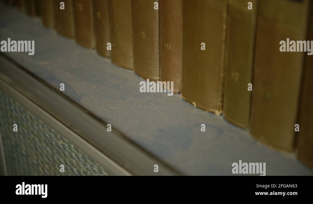 Woman's hand dusting dust off dirty old library book shelf 4K Stock