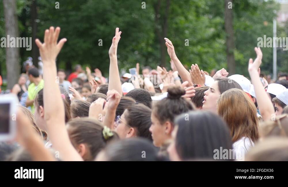 Young spectators fans crowd people cheering sway hands in air by a