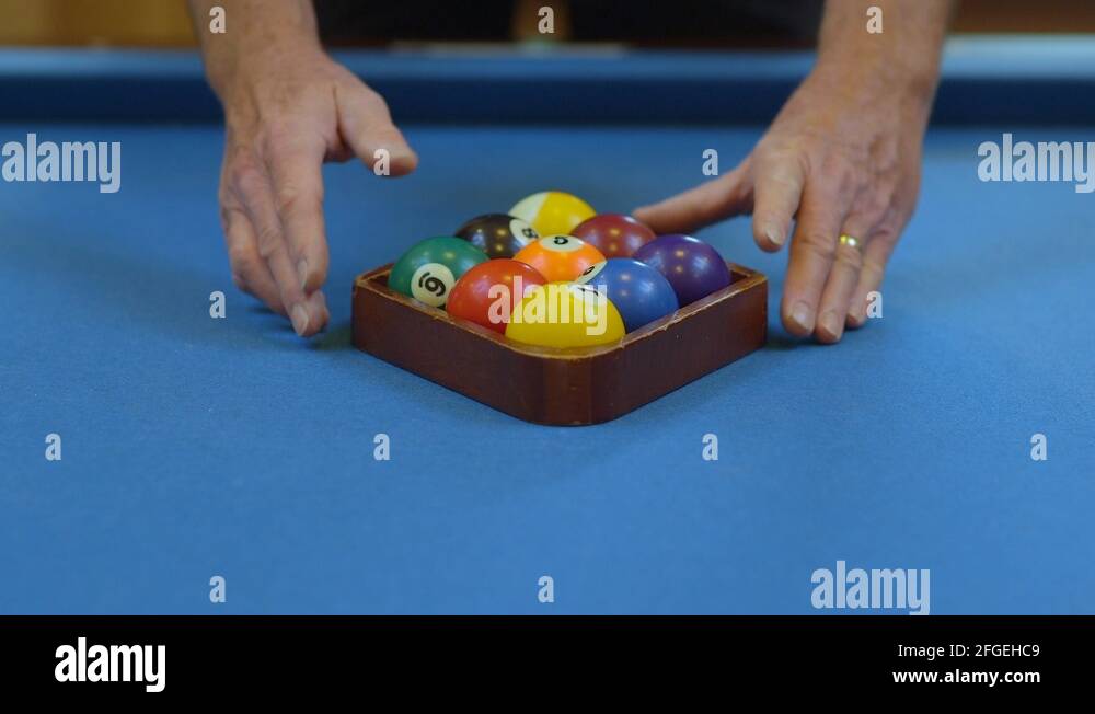 Man Racking Pool Balls in NineBall Formation on Blue Billiards Table