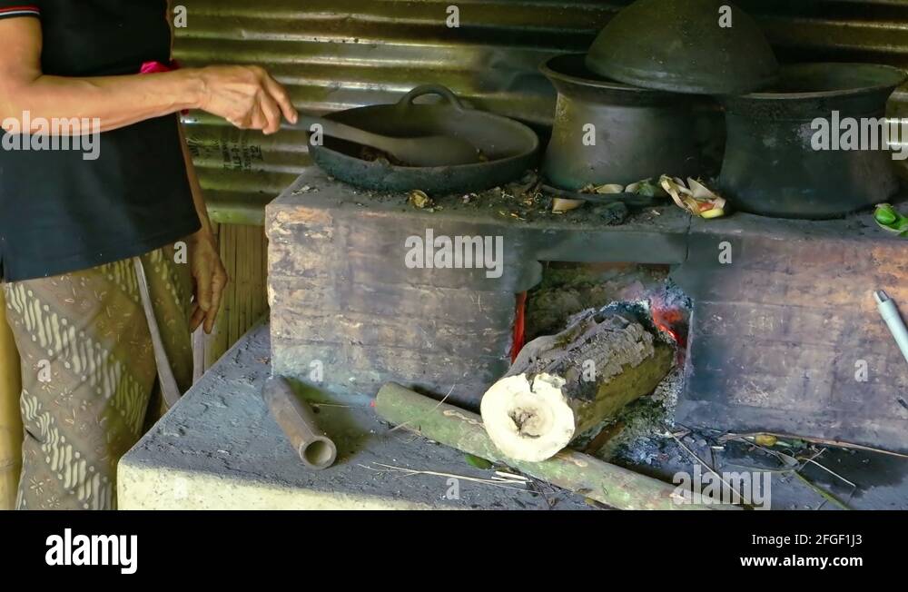 Balinese woman roasting coffee beans in a cast iron pan, over a wood