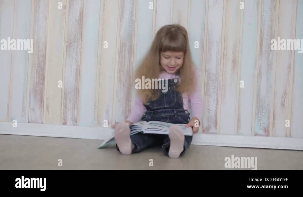 little girl reading a book sitting on floor Stock Video Footage - Alamy