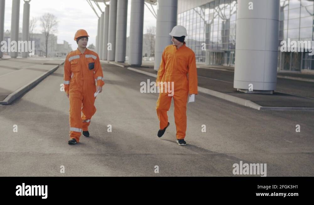 Two construction workers in orange uniform giving high five. They look ...
