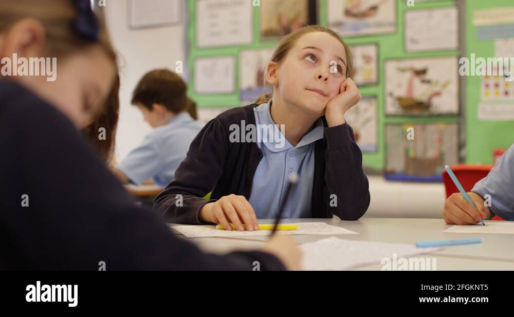 4K Portrait of bored little girl in school classroom daydreaming at her ...