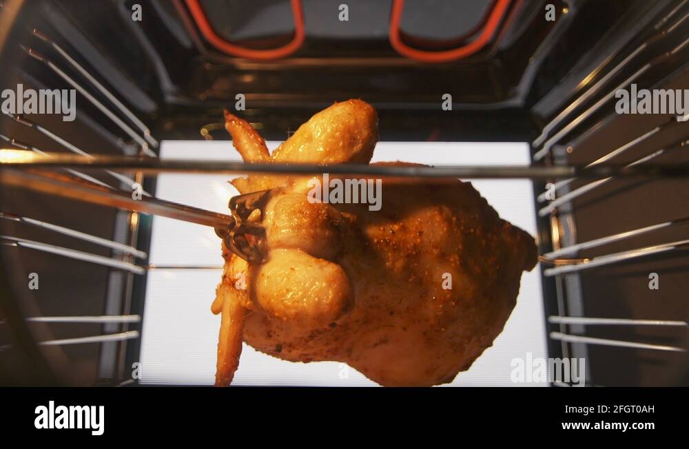 Cooking roasted whole chicken on the rotisserie spit in hot convection