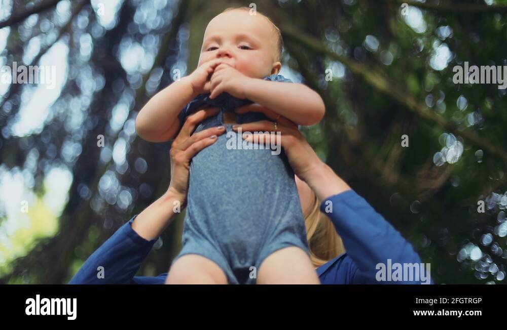 Happy playing together mother throwing baby up laughing summer sun rays