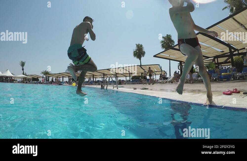 Two boys jump feet first while swirling on a Turkish resort in slomo
