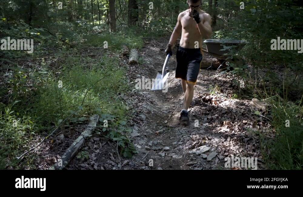 Man Digging Rocks Young shirtless man digging dirt and rocks with a square shovel and ...