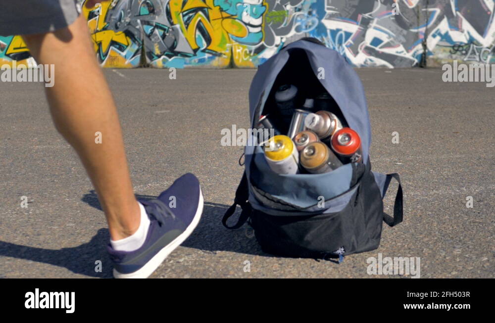 Opened backpack filled with spray paint is getting taken off the ground