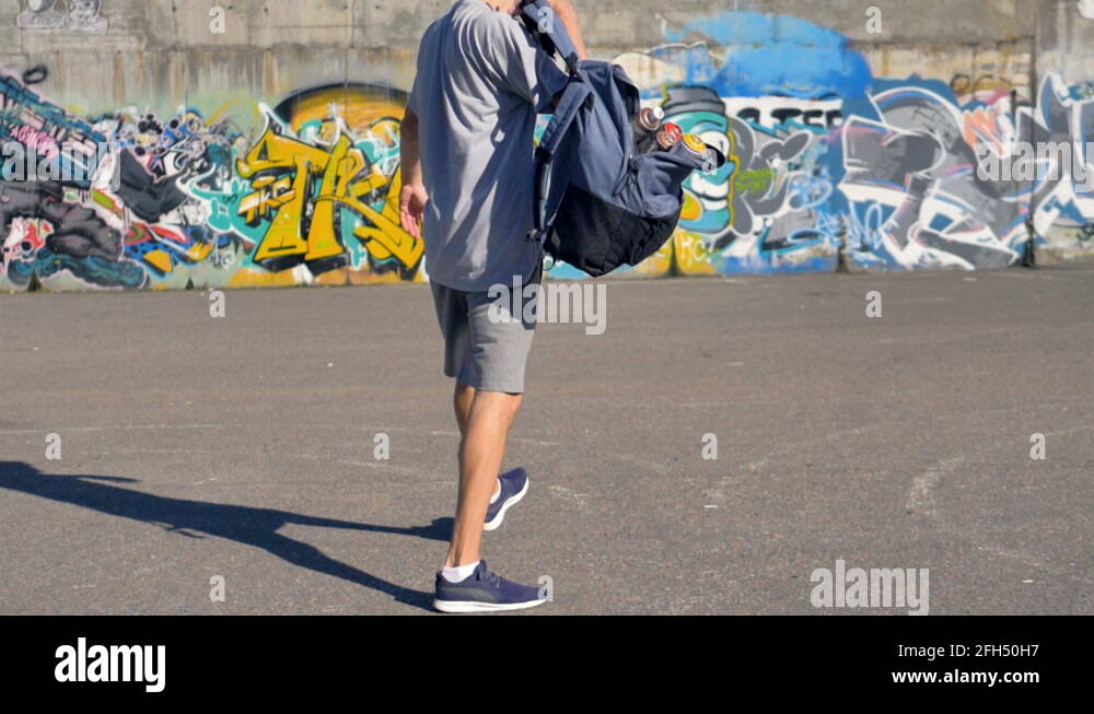 Graffiti artist is lifting his backpack with paint canisters and going