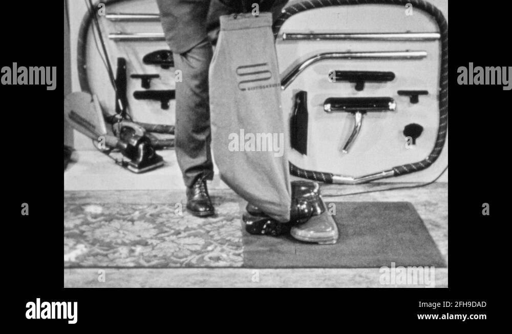 1940s Salesman lifts and turns vacuum. Salesman demonstrates vacuum