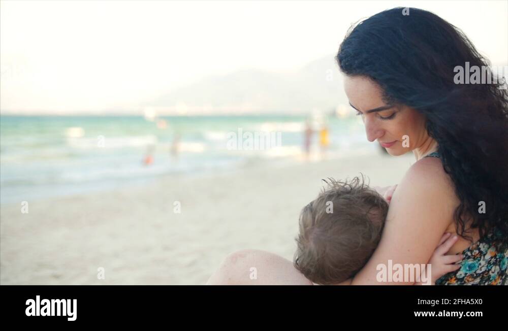 Mom with baby are enjoying fresh air sit by the sea, mom is