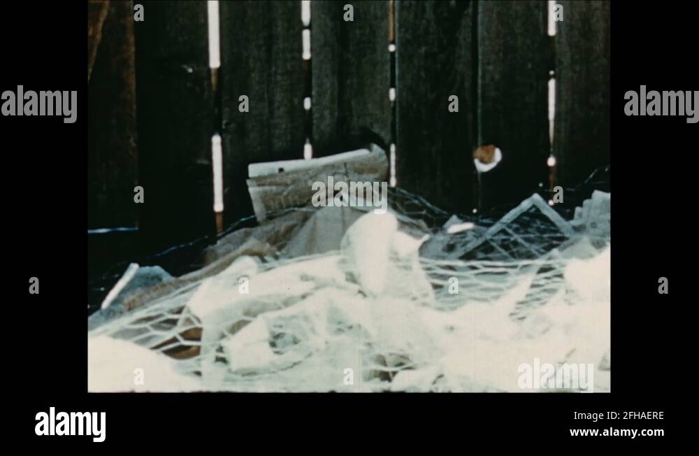 1950s: UNITED STATES: trash at base of old fence. Explosion in desert ...