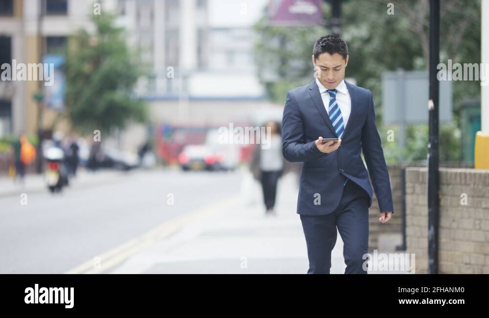 Handsome man in a suit punches the air as he looks happily at his phone