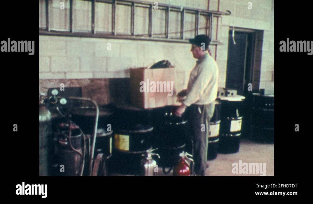 1970s Man carries box from chemical drums. Man covers drums with cloth. Sparks Stock Video