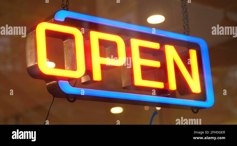 Blue and Orange Neon Open Sign is lit in front of a glass store front ...