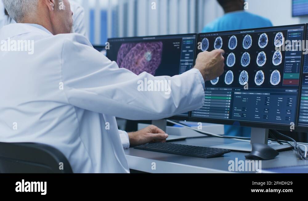 Two Medical Scientists Discussing CT / MRI Brain Scan Images on a PC ...