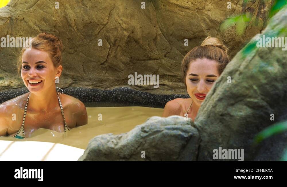 Two young woman taking mud bath in luxury spa center. Happy woman ...