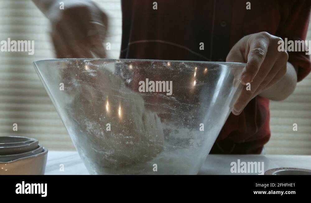 Close up of woman's hands kneading dough in the kitchen to be made into ...