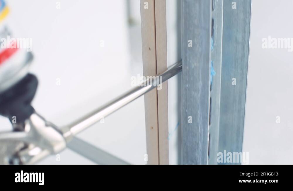 Laborer uses a tool to apply insulation to a new door frame in a home