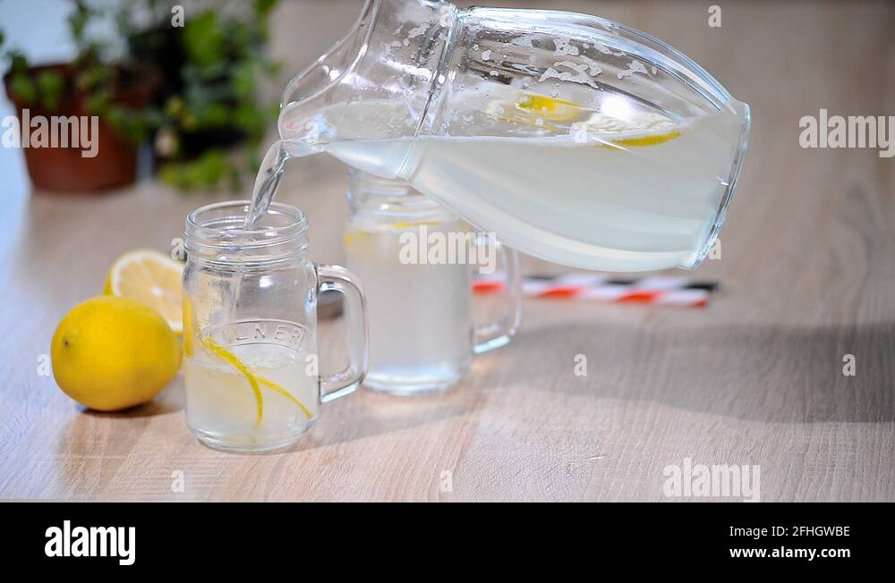 Pouring homemade lemonade soda drink to glass with lemon Stock Video