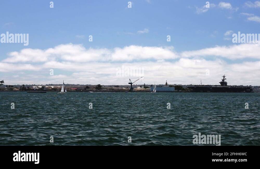 A boat for tourism sails across a clam harbor from left to right Stock