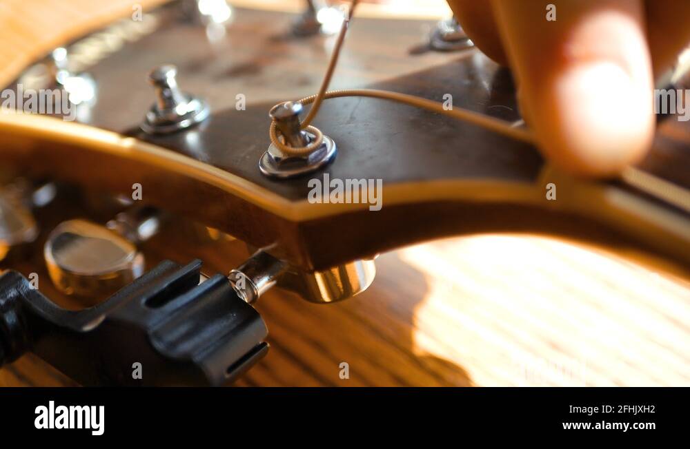 Replacing the strings on an acoustic guitar at the headstock Stock