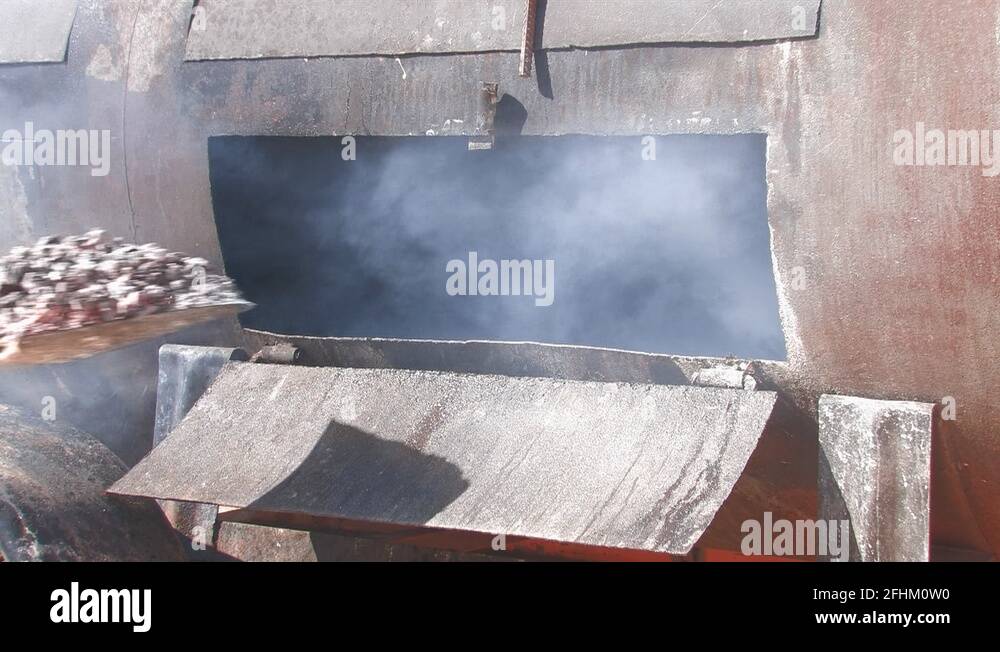 Shoveling hot coals into a large barbecue wagon Stock Video Footage Alamy