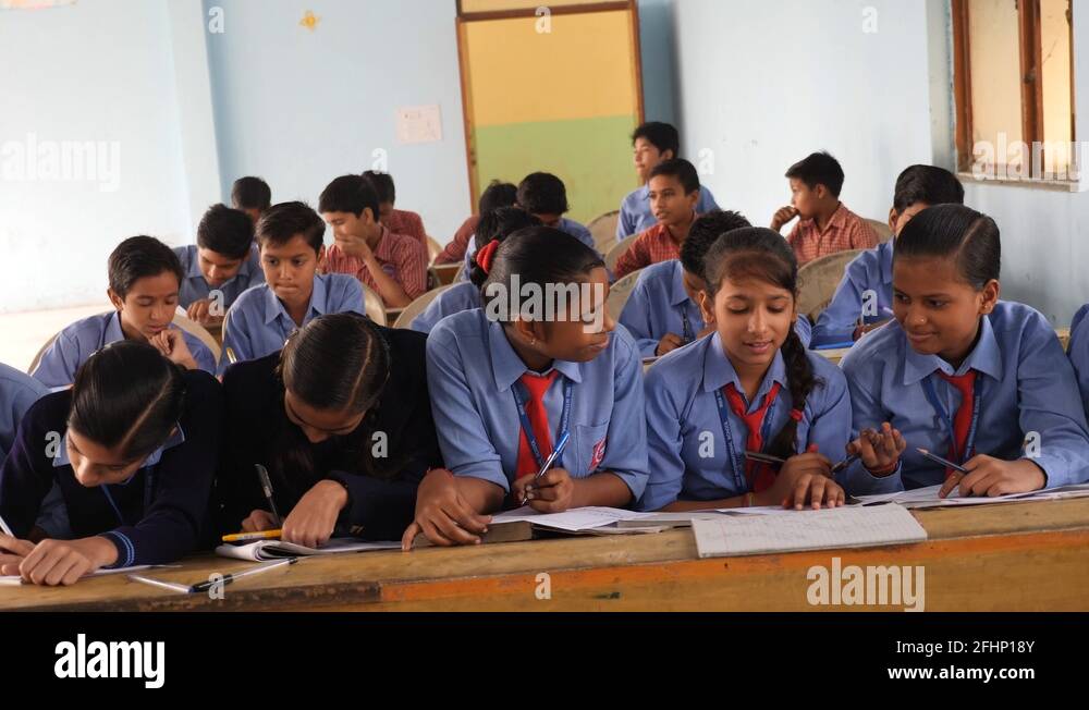 Indian girl students chatting and studying in a classroom, aware of the ...
