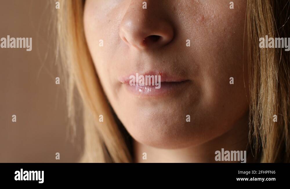 Woman touches the sores from herpes on her lips. Women's lip ulcers