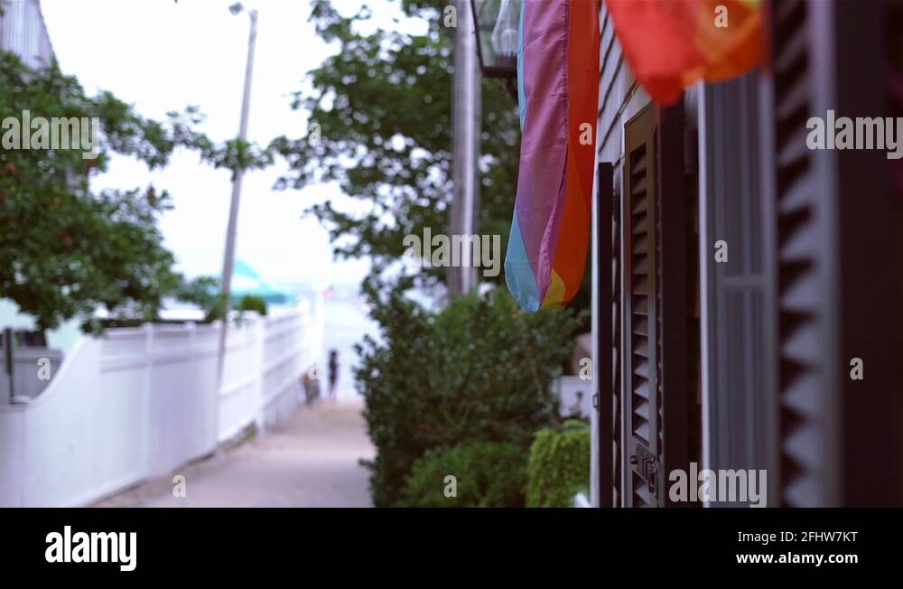 A pride flag waving in the wind in an alley in provincetown with a
