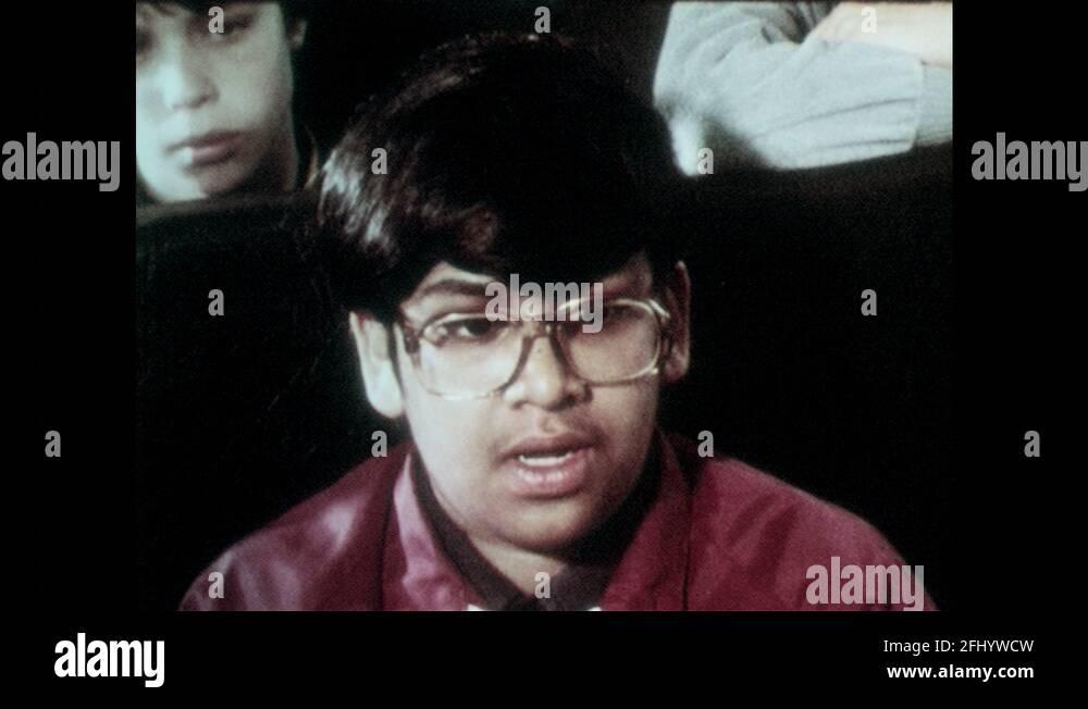 1980s: Children sit on school bus, boy talks, looks indignant. Children ...