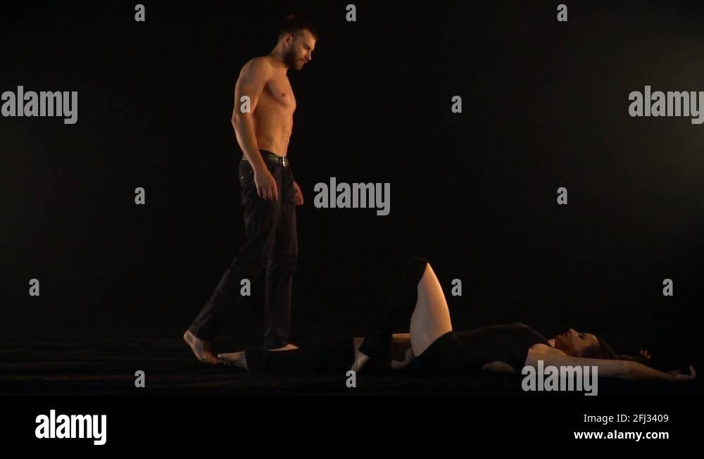 Athletic man comes to a lying woman and lifts her in his arms, slow ...