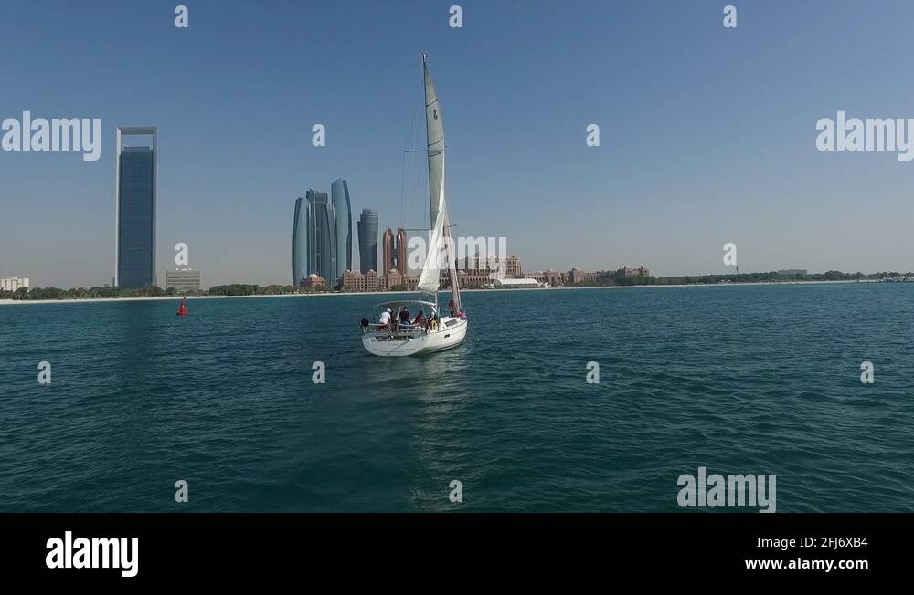 Sailing boat cruising around a green sea near Emirates Palace in Abu